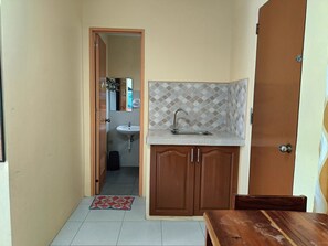 A small kitchen with a sink, wooden cabinets, and a tiled backsplash. - Allen Marie Shiphaus powered by Cocotel (Santa Fe)