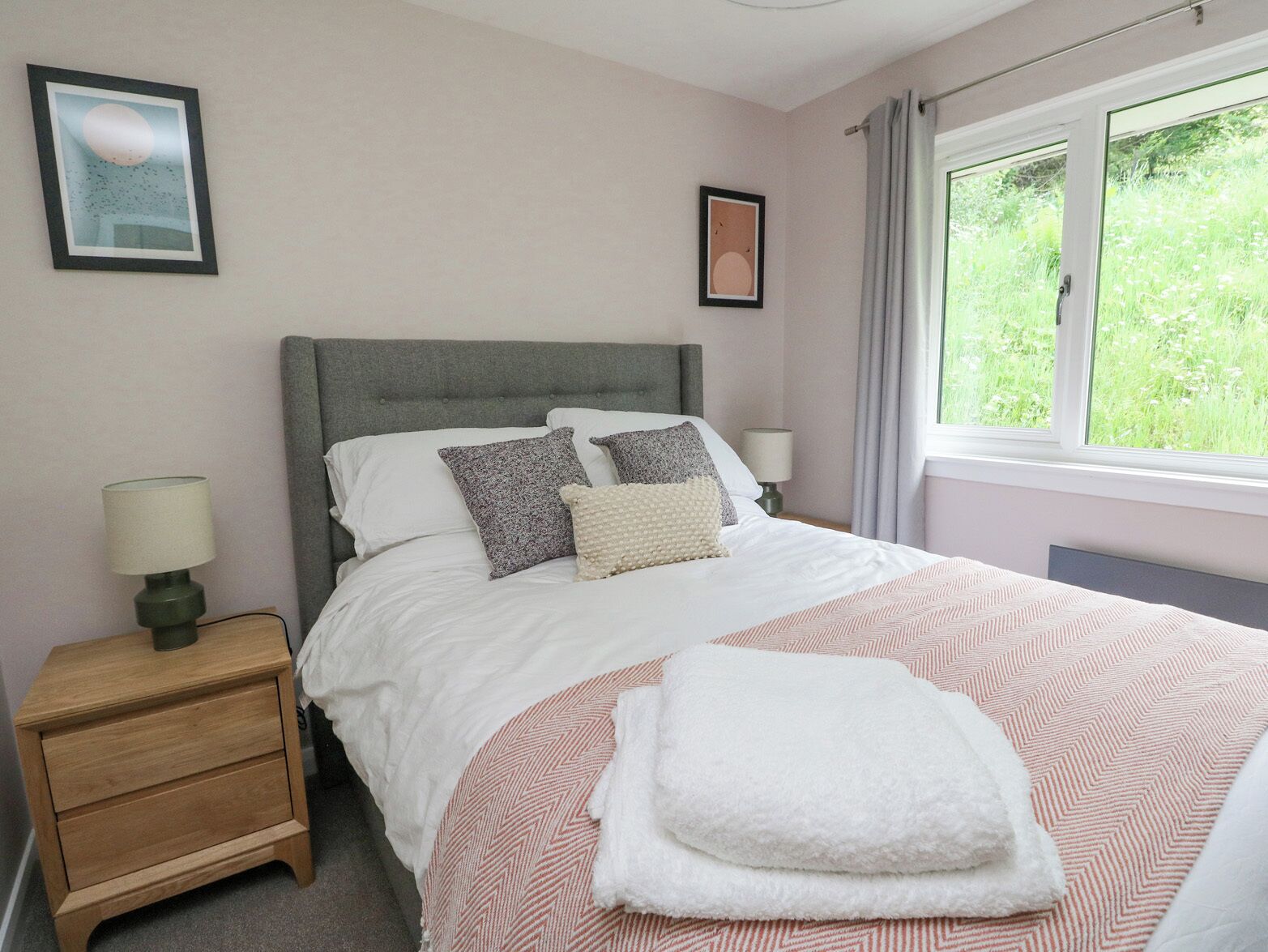 A bedroom with a bed, bedside tables, and a window with curtains.