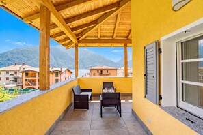 A balcony with a wooden pergola, two chairs, a table, and a window with shutters. - Casa Veligato 2 (San Siro)