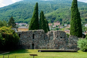 A historic stone building with a grassy foreground and a mountainous backdrop. - Casa Veligato 2 (San Siro)