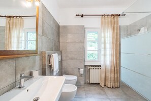 A modern bathroom with a large bathtub, a toilet, and a shower area.
