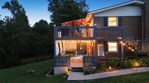 A two-story house with a balcony, outdoor seating, and string lights. - The Asheville House, Family Home with Hot Tub and Game Room (Asheville)