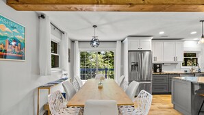Una cocina moderna con armarios blancos, una mesa de comedor de madera y sillas blancas.