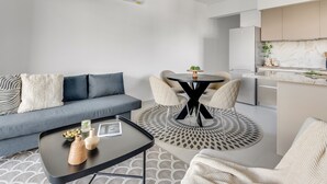 A modern living room with a sofa, coffee table, and a round dining table. - Sanders Triple - Cozy 1-bdr Apt With Balcony (Limassol)