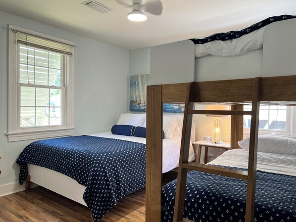 A room with two bunk beds, a window with blinds, a painting on the wall, and a bedside table with a lamp. - King Bed/ Walk to the Beach/ Hammock/ Family summer Fun (Gulfport)