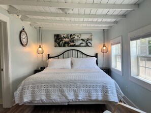 A bedroom with a bed, two bedside lamps, a clock, and a window.
