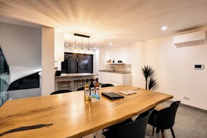 Uma sala de jantar moderna com uma mesa de madeira, cadeiras pretas e vista para a cozinha.