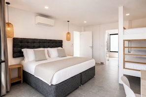 A modern bedroom with a large bed, bedside tables, a built-in bench, and a view of the hallway.