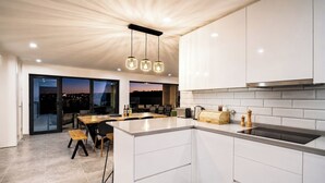 Una cocina moderna con armarios blancos, una isla central e iluminación colgante.