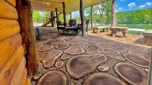 A covered outdoor area with wooden flooring, seating, and a view of a lake. - “Triple Timbers” 18 bdrm,sleeps 56! hotubs, docks, 5 firepits, sxs, rent boats (Lafollette)