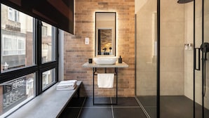 Un baño moderno con un ventanal grande, lavabo integrado y mampara de ducha de vidrio.