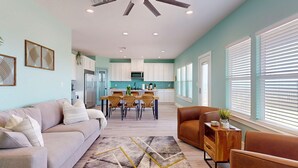 A modern living room with a sofa, a coffee table, and a dining area with a table and chairs. - Tiffany House: 4  BR, 3.5  BA House in Crystal Beach, Sleeps 16 (Bolivar Peninsula)