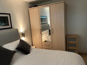 Comfortable retreat with a large wardrobe, bed, and bedside table.