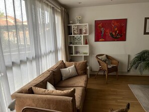 Relax in this inviting living room with a leather sofa, wicker chair, and a large window offering a view.