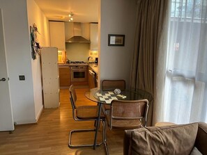 Cozy living space with a kitchenette, glass-top dining table, and comfortable sofa.