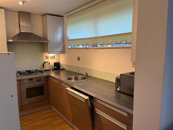 Enjoy cooking in this compact kitchen with a gas stove, oven, and dishwasher, all integrated into sleek cabinetry.