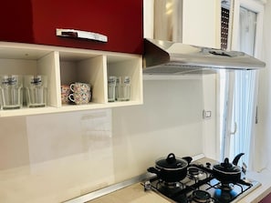 Cozinha com fogão a gás, panelas e uma parede vermelha.