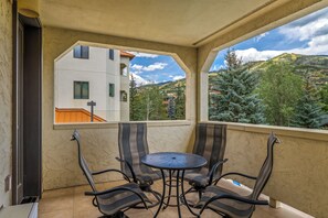 A balcony with a table and four chairs, overlooking a residential area with houses and trees. - Luxury Mountain Escape| The Terraces at EagleRidge! (Steamboat Springs)