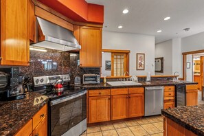 A modern kitchen with granite countertops, stainless steel appliances, wooden cabinets, and a large window. - Luxury Mountain Escape| The Terraces at EagleRidge! (Steamboat Springs)