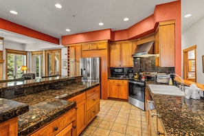 A modern kitchen with granite countertops, stainless steel appliances, wooden cabinets, and a large window. - Luxury Mountain Escape| The Terraces at EagleRidge! (Steamboat Springs)