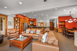 A spacious living room with leather sofas, a coffee table, and a dining area with wooden chairs and a chandelier. - Luxury Mountain Escape| The Terraces at EagleRidge! (Steamboat Springs)