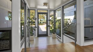 A modern interior with large glass doors leading to a garden, wooden flooring, and potted plants. - Waterfront Oasis: Dock, Recreation Hall & Pet-Friendly! (Wilmington)