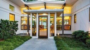 A modern house with a glass door entrance, a covered patio, and a well-maintained garden. - Waterfront Oasis: Dock, Recreation Hall & Pet-Friendly! (Wilmington)