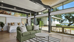 A spacious living room with a green sofa, a white coffee table, and a large window overlooking a lake. - Waterfront Oasis: Dock, Recreation Hall & Pet-Friendly! (Wilmington)