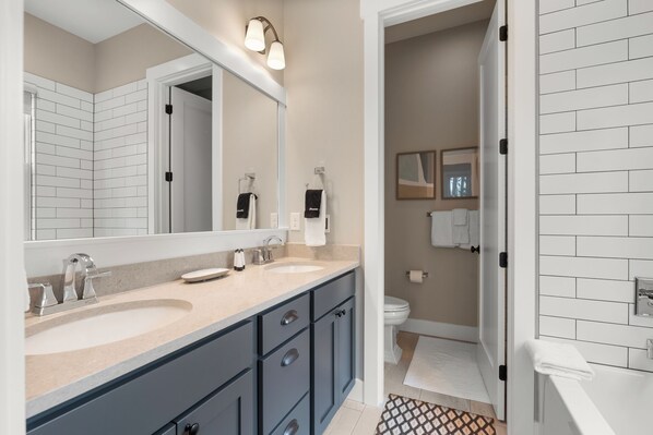 A modern bathroom with two sinks, a large mirror, and a walk-in shower.