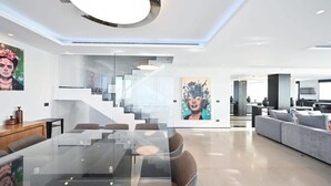 Un salon moderne avec une table à manger en verre, un canapé et un escalier menant à un niveau supérieur.