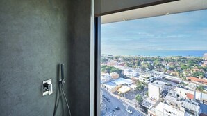 Une salle de bain dotée d’une grande fenêtre donnant sur la ville.