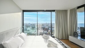 Une chambre d’hôtel moderne avec un grand lit, une télévision et une vue sur la ville.
