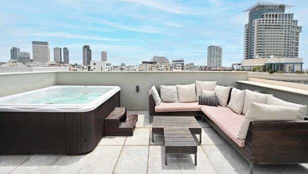 Une terrasse sur le toit dotée d’un jacuzzi, d’un espace salon et offrant une vue panoramique sur la ville.