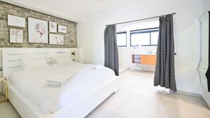Une chambre d’hôtel moderne avec un grand lit, un mur décoratif en briques et une vue sur la salle de bain.