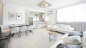 Un salon moderne avec un coin repas, un ensemble de canapés et une cuisine en arrière-plan.