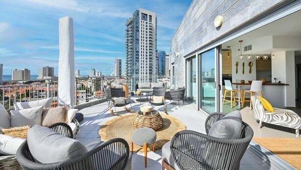 Une terrasse sur le toit avec des espaces de détente en plein air, une cuisine moderne et une vue sur la ville.