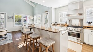 Cozinha moderna com ilha central, eletrodomésticos de aço inoxidável e vista para o exterior.