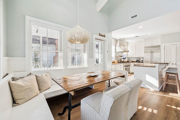 A modern kitchen with white cabinetry, a wooden dining table, and a built-in island.