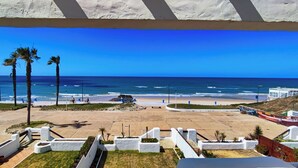 Blick auf einen Strand mit Palmen, Sand und Booten.