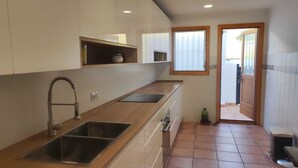 Eine Küche mit modernem Design, ausgestattet mit einem Edelstahlspülbecken, einem eingebauten Backofen und einem Fenster mit Jalousien.