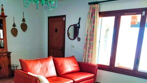 Ein Wohnzimmer mit einem roten Ledersofa, einem Holztisch und einem gemusterten Teppich.