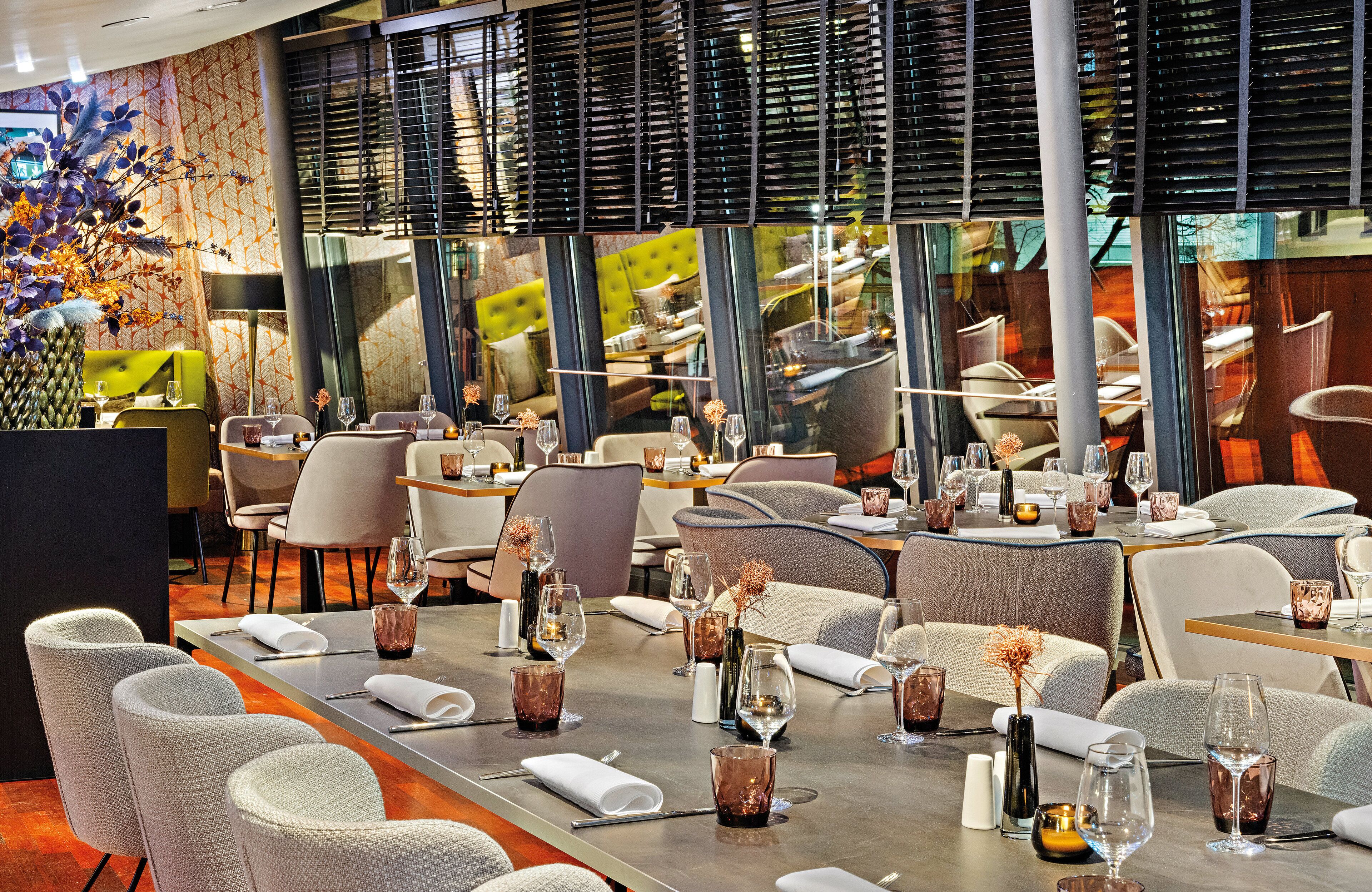 A modern restaurant with high tables, comfortable seating, and a decorative centerpiece.