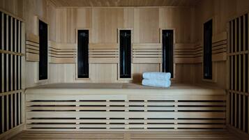 A sauna with wooden walls and benches, a towel on the bench, and ventilation panels.