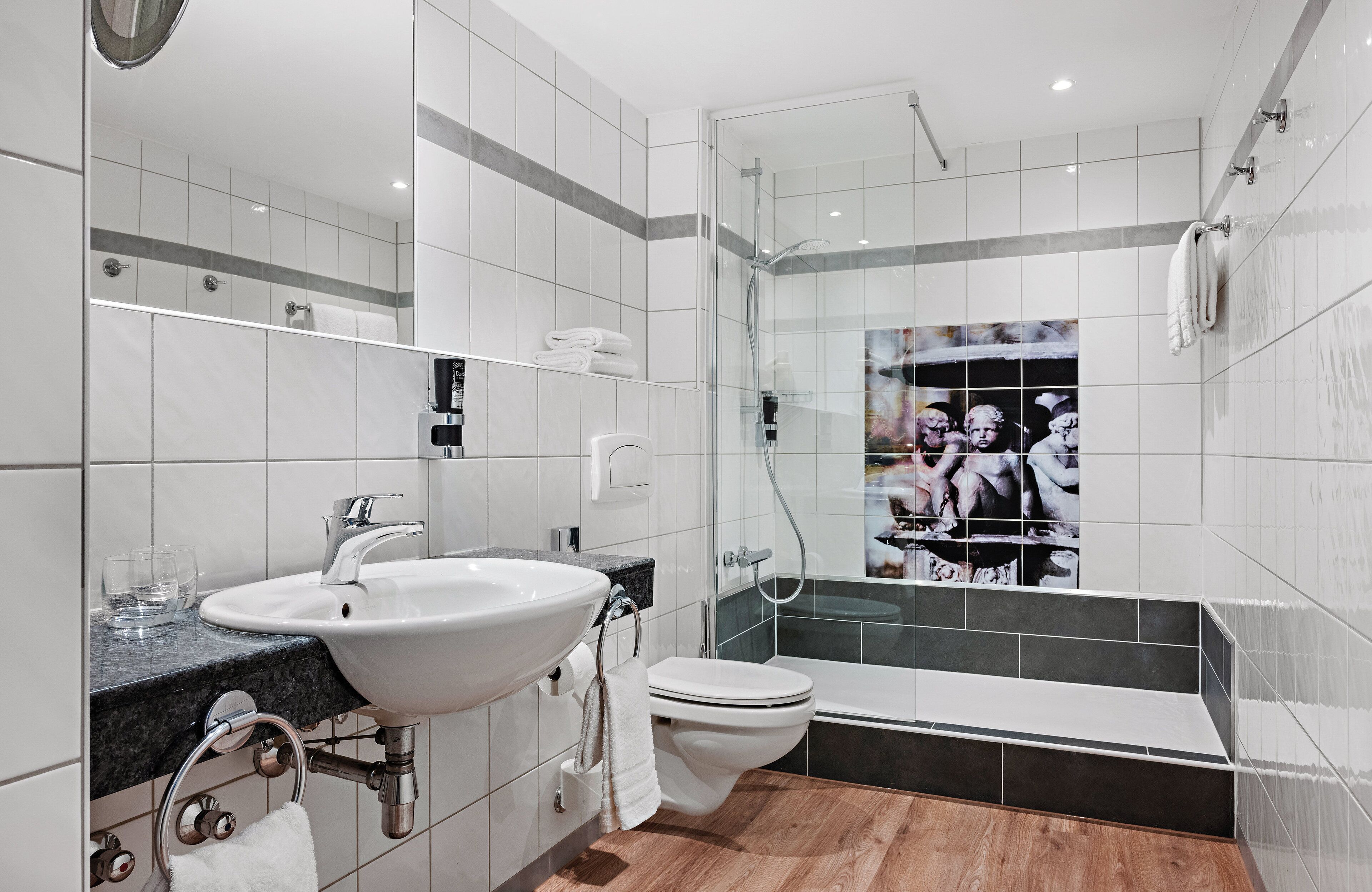 Un baño moderno con lavabo, inodoro y ducha con mampara de vidrio.