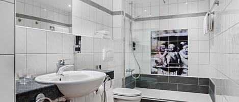 Un baño moderno con lavabo, inodoro y ducha con mampara de vidrio.
