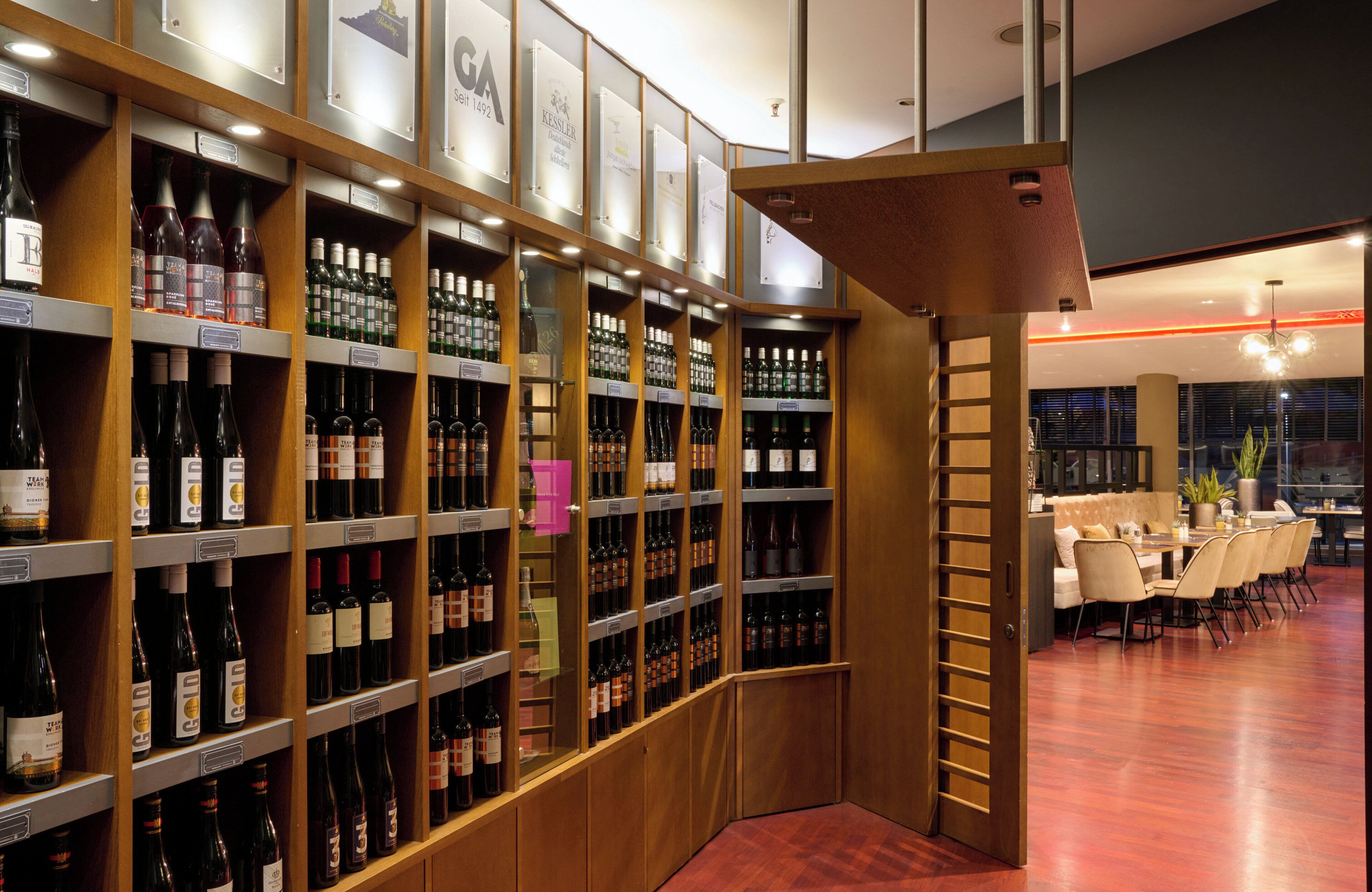A wine cellar with wooden shelves and a dining area with a table and chairs.
