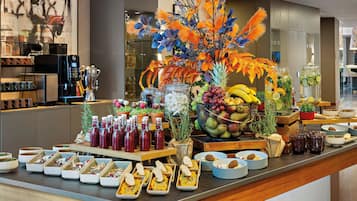 A buffet with various food items and beverages, including fruits, salads, and drinks.