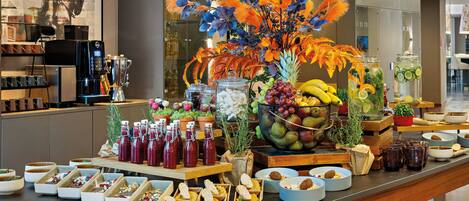 A buffet with various food items and beverages, including fruits, salads, and drinks.