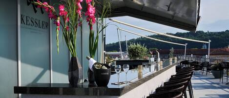 A bar area with a counter, chairs, and a view of the landscape.