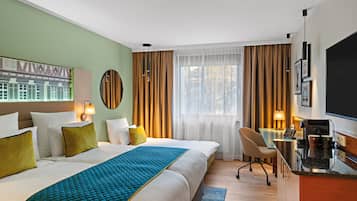 A hotel room with a large bed, a desk with a chair, a television, and a window with curtains.